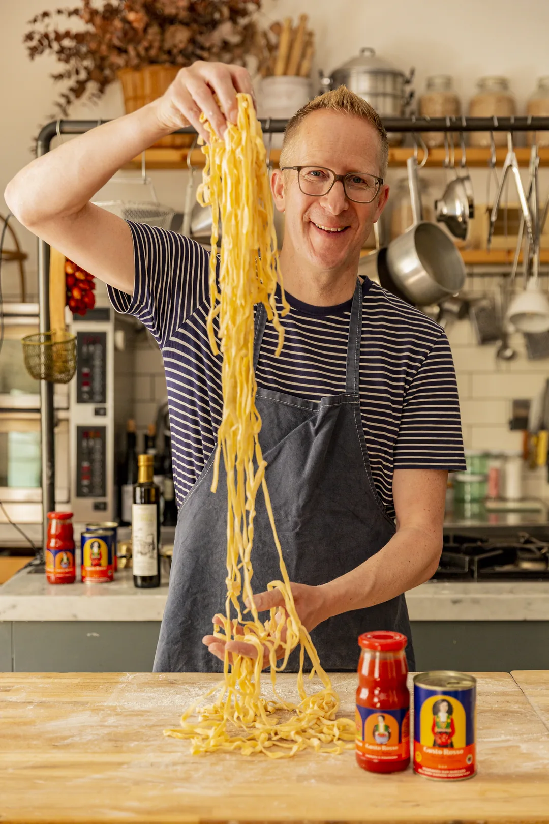 Jens Depenau hebt frische Tagliatelle über einem bemehlten Holztisch in die Höhe